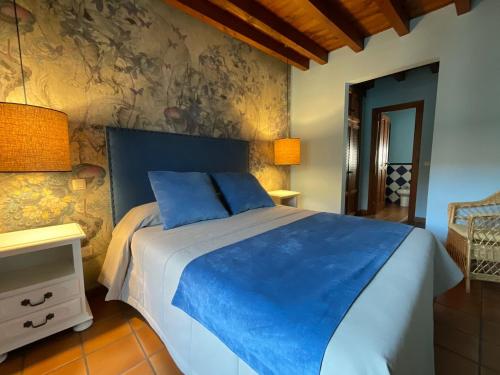 - une chambre dotée d'un grand lit avec des draps bleus dans l'établissement Posada Albarea, à Candeleda