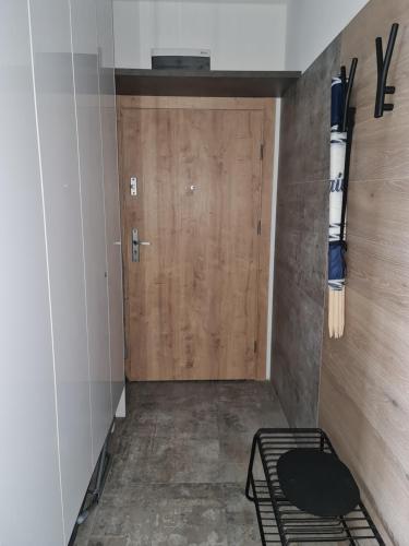a locker room with a wooden door and a bed at Porta Mare Apartments LuxView- Budynek Centralny in Dziwnówek