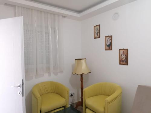 twee gele stoelen in een kamer met een lamp bij Apartmani Glorija in Arandjelovac