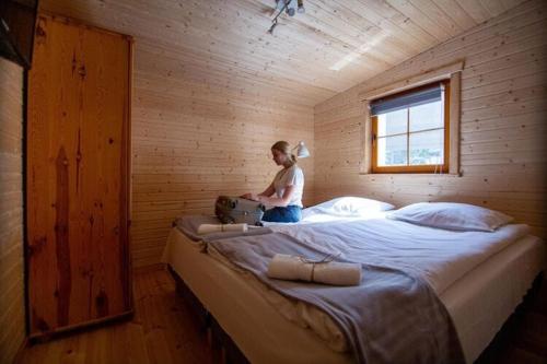 una mujer sentada en una cama grande en una habitación de madera en Bungalow, Miedzyzdroje en Międzyzdroje