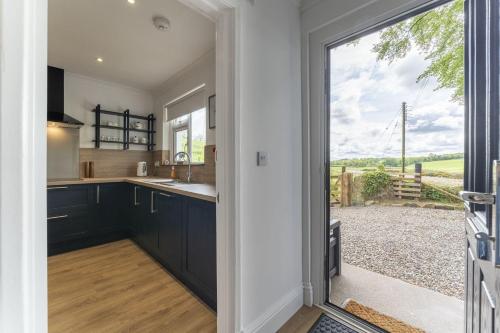 a kitchen with black cabinets and a large window at Wilsons Cottage in Falkirk