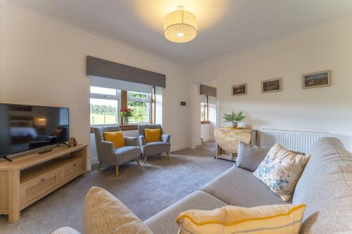 a living room with a couch and a flat screen tv at Wilsons Cottage in Falkirk