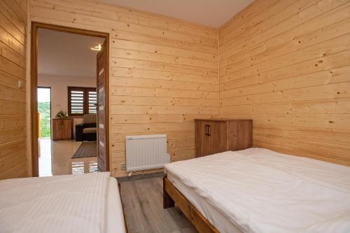 two beds in a room with wooden walls at Apartamenty u Bartka i Magdy in Solina