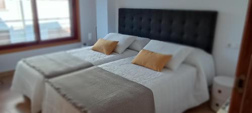 1 dormitorio con 1 cama blanca y 2 almohadas en Zárate 3G, en Portonovo