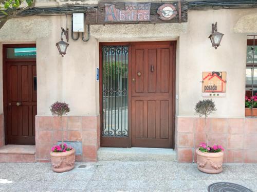 une porte d'entrée d'un bâtiment avec deux plantes en pot dans l'établissement Posada Albarea, à Candeleda