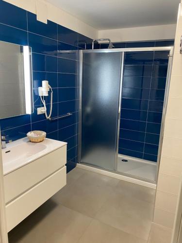 y baño de azulejos azules con ducha y lavamanos. en Torre del mare Rooms, en Bergeggi