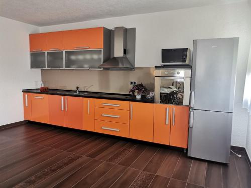 een keuken met oranje kasten en een roestvrijstalen koelkast bij Apartman Sali in Bihać