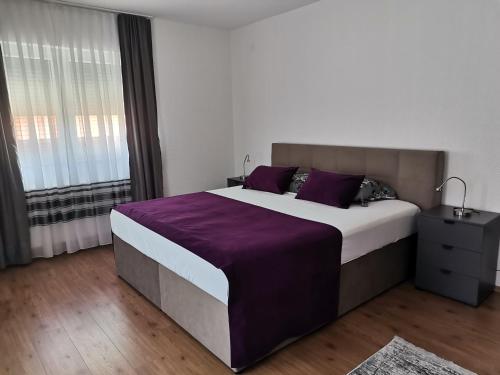 een slaapkamer met een groot bed met paarse lakens bij Apartman Sali in Bihać