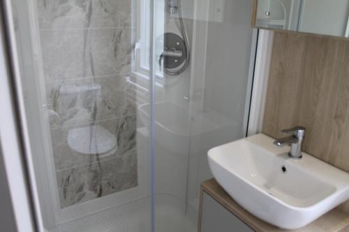 uma casa de banho com um chuveiro, um lavatório e um chuveiro em luxury new 3 bed caravan with stunning sea view on private beach in Thorness bay em Porchfield