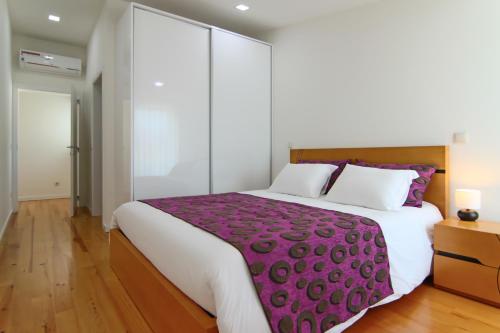 a bedroom with a large bed with a purple blanket at Varandas de S. Jorge - Apartments in Arcos de Valdevez