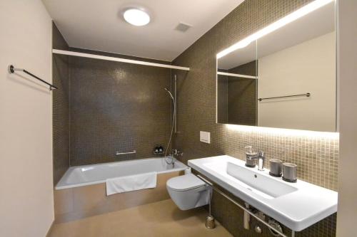 ein Badezimmer mit einem Waschbecken, einer Badewanne und einem WC in der Unterkunft Dream View Apt With Homecinema Netflix & Loggia in Luzern