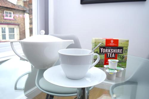 a white coffee cup sitting on a table next to a window at Malton Central Apartments in Malton
