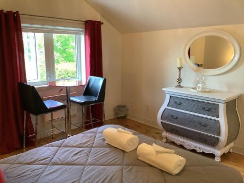 a bedroom with a bed and a mirror and a table at Les saisons du fleuve in Lotbinière