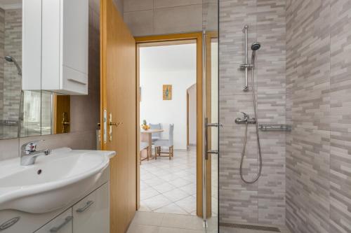 uma casa de banho com um lavatório e um chuveiro com uma porta de vidro em App Ružica Finida em Umag