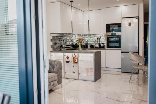 a kitchen with white cabinets and a counter with chairs at Apartament Villa Klar in Ostróda