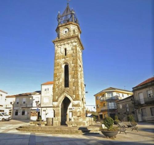 Una torre de piedra alta con un reloj. en Casa Cea Ourense, en Cea