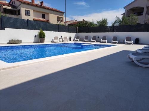 een zwembad met stoelen naast een huis bij Viktor rooms and apartments in Rovinj