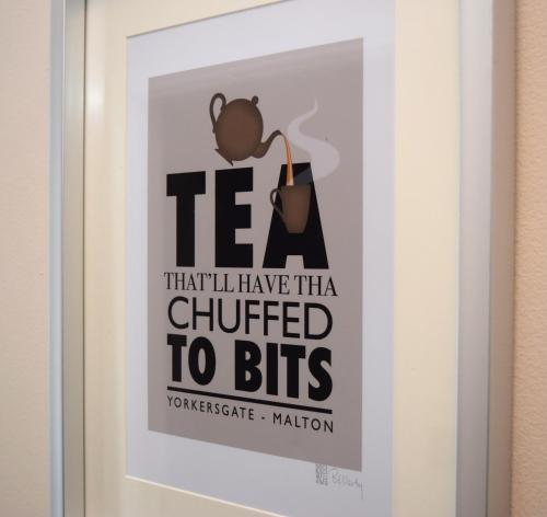 a framed poster of a woman holding a pot at Malton Central Apartments in Malton