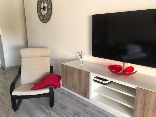 a living room with a large television and a chair at Cozy apartment in Los Cristianos in El Guincho