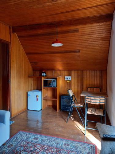 a living room with a table and a refrigerator at Bongusto Apart House Locações Mantiqueira in Monte Verde