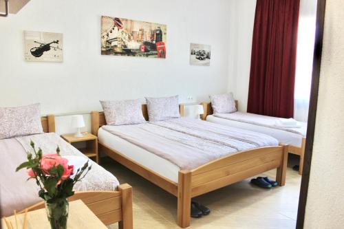 a bedroom with two beds and a vase of flowers on a table at Becar Pyramid Rooms in Visoko
