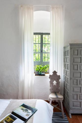 a bedroom with a bed and a window and a chair at Finca San Juan Alojamiento Boutique in Constantina