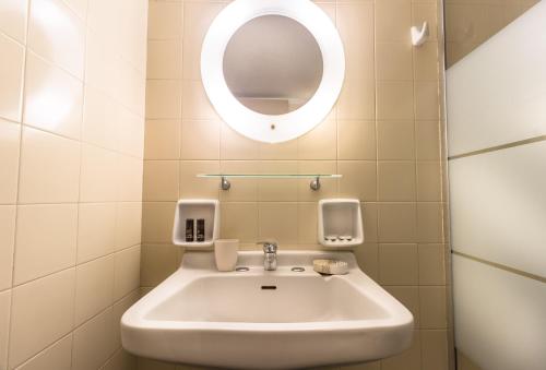 a bathroom with a white sink and a mirror at Blue Era Apartments in Batsi