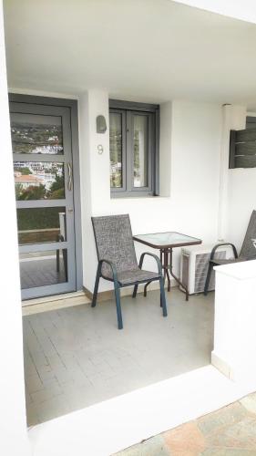 a patio with two chairs and a table and a window at Blue Era Apartments in Batsi