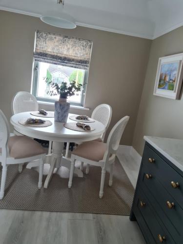 a white dining room table with chairs and a window at The Little White House in Tyrrellspass
