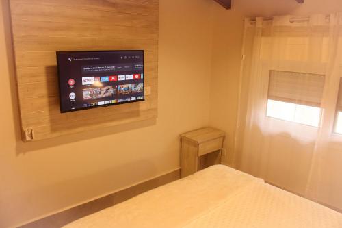 a bedroom with a flat screen tv on the wall at Casa d'Aroeira Residencial Boutique - Centro de Juqueí - 2 quadras do mar - Serviço de Praia - Roupa de Cama 600 fios algodão Egípcio - Toalhas Banho e Praia - Tudo Novo - Estacionamento Interno - Cozinha - Consulte unidades com Ofurô Hidro e Cromoterapia in Juquei