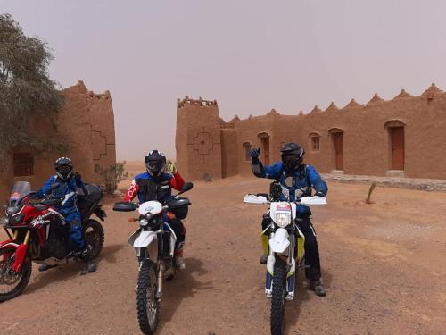 three people riding motorcycles on a dirt road at Auberge Dinosaur Kem Kem in Tafraoute Sidi Ali