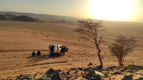 a group of people sitting in the desert at Auberge Dinosaur Kem Kem in Tafraoute Sidi Ali