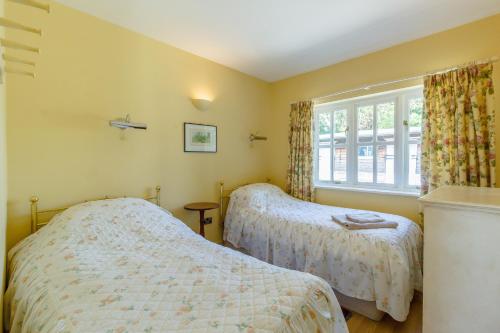 1 dormitorio con 2 camas y ventana en Curlew Cottage, en Hexham