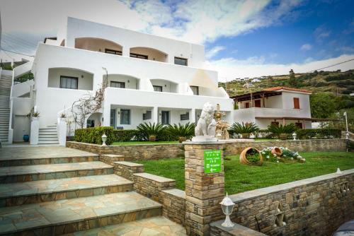 a large white house with a statue in front of it at Blue Era Apartments in Batsi