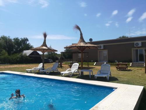 eine Person, die in einem Pool mit Stühlen und Sonnenschirmen schwimmt in der Unterkunft Soles de Alicia in Colón
