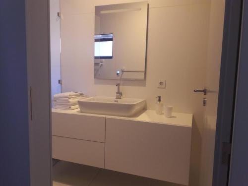 uma casa de banho branca com um lavatório e um espelho em Maia Centro em Maia