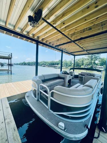 a boat sitting on the water with a dock at The Benjamin I - 2022 Built Luxury Retreat with Backyard Paradise with Hot Tub Outdoor Movie Screen Dock & Boat Rental in Gun Barrel City