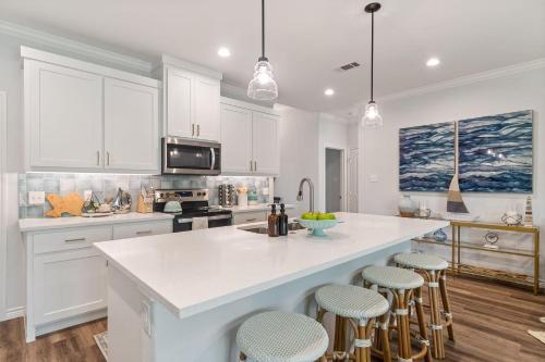 a kitchen with white cabinets and a large island with bar stools at The Benjamin I - 2022 Built Luxury Retreat with Backyard Paradise with Hot Tub Outdoor Movie Screen Dock & Boat Rental in Gun Barrel City