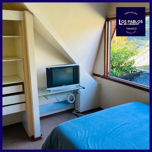a bedroom with a bed and a tv and a window at B&B Los Pablos Temuco in Temuco