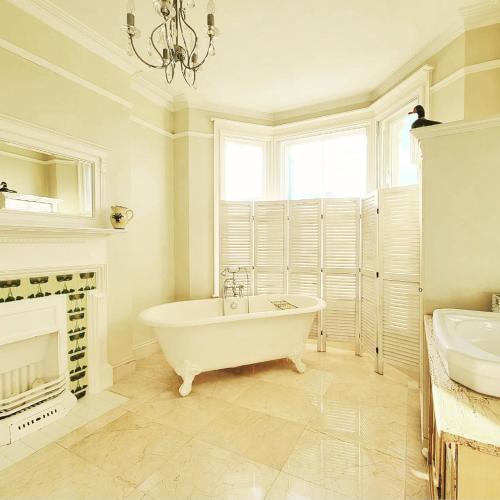 a white bathroom with a tub and a fireplace at West Hill Retreat Edwardian Balcony Grand Ensuite with Room Served Breakfast & Free Offstreet Parking in Hastings