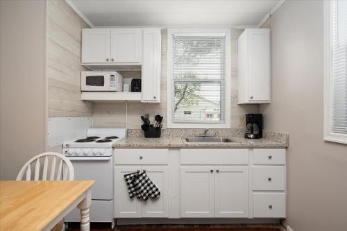 a kitchen with white cabinets and a sink and a microwave at Beach Bum West-O Cabins in Ocean City