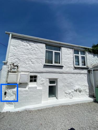 a white building with windows and a blue box at St Ives Balcony Flat in St Ives