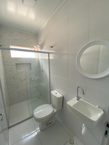 a bathroom with a toilet and a sink and a mirror at Village Caranguejo - Flat com 02 Quartos in Aracaju