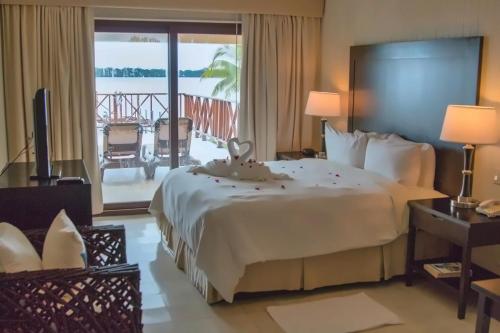 a hotel room with a large bed and a balcony at Playa Tortuga Hotel and Beach Resort in Bocas del Toro