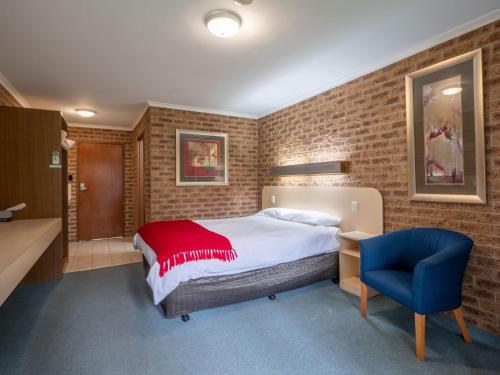 1 dormitorio con 1 cama y 1 silla azul en Eildon Parkview Motor Inn Room 1, en Eildon