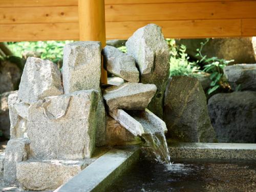 a water fountain in a garden with rocks at Pension Asanebou in Minakami