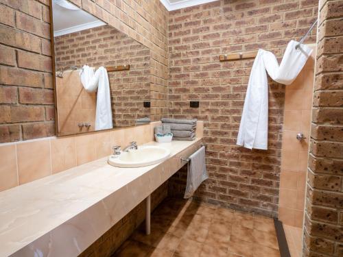 a bathroom with a sink and a brick wall at Eildon Parkview Motor Inn Room 2 in Eildon