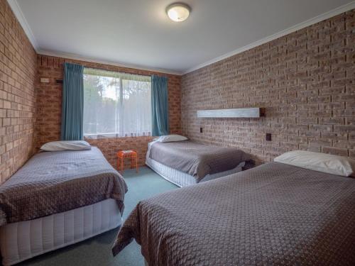 a bedroom with two beds and a brick wall at Eildon Parkview Motor Inn Room 10 in Eildon