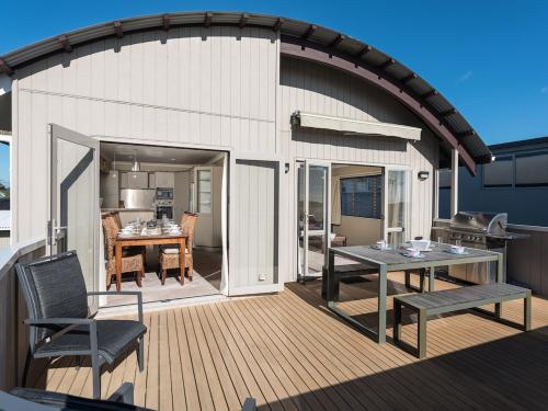 an outdoor deck with a table and a grill at A Beach Barn Haven - Papamoa Holiday Home in Papamoa
