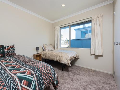 una camera da letto con due letti e una finestra di A Beach Barn Haven - Papamoa Holiday Home a Papamoa